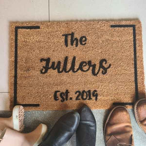 Doormat that says The Family name and year, Fullers est. 2019. There are the families shoes around the doormat.