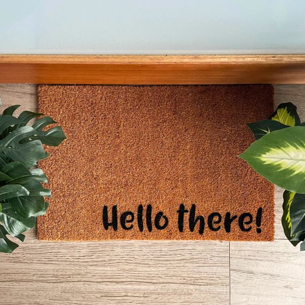 Doormat that says 'Hello there!' surrounded by plants
