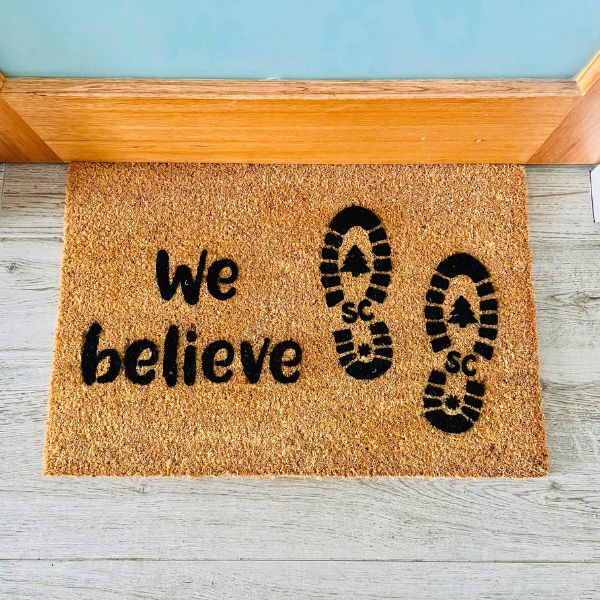 Doormat that says 'We believe' and has Santa's footprints on it