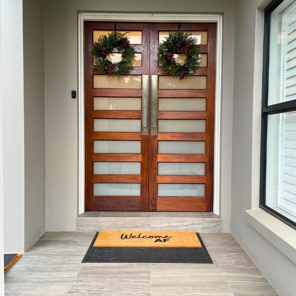 Large Welcome AF Doormat outside with wreaths on door