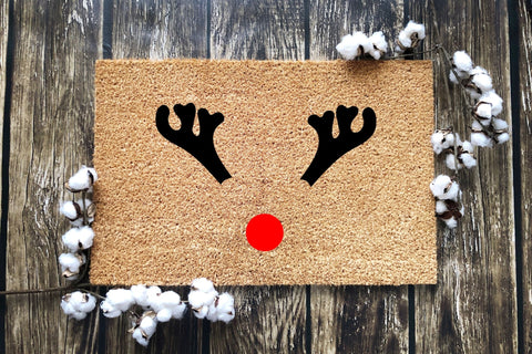 A doormat with reindeer antlers and a red nose